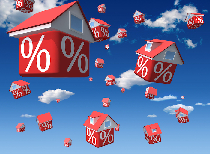 Falling houses with percent symbol on sky background