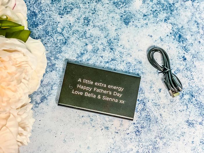 Treat Republic Personalised Engraved Black Powerbank that says: "A little extra energy Happy Father's Day Love Bella & Sienna xx"