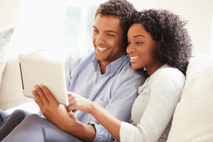 young couple searching on a tablet sitting on a couch