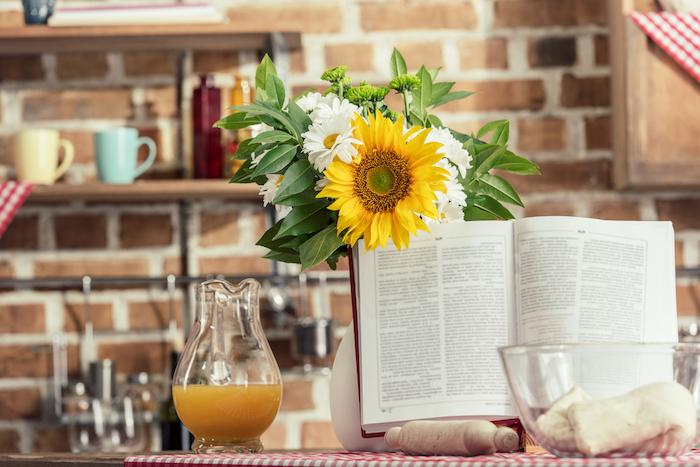 Recipe book and bouquet of flowers on cooking table at kitchen — Photo