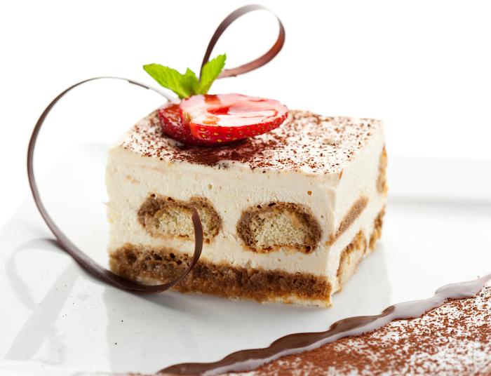 Tiramisu - Classical Dessert with Cinnamon and Coffee. Garnished with Strawberry and Mint