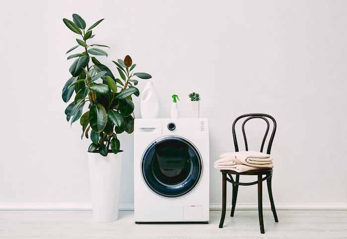 Modern washing machine with a plant and chair next to it