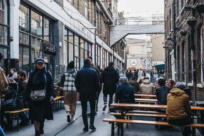 London, UK - December 29, 2019: People walking on Dray Walk towards Elys Yard, a popular industrial-style street food market just off Brick Lane, East London.