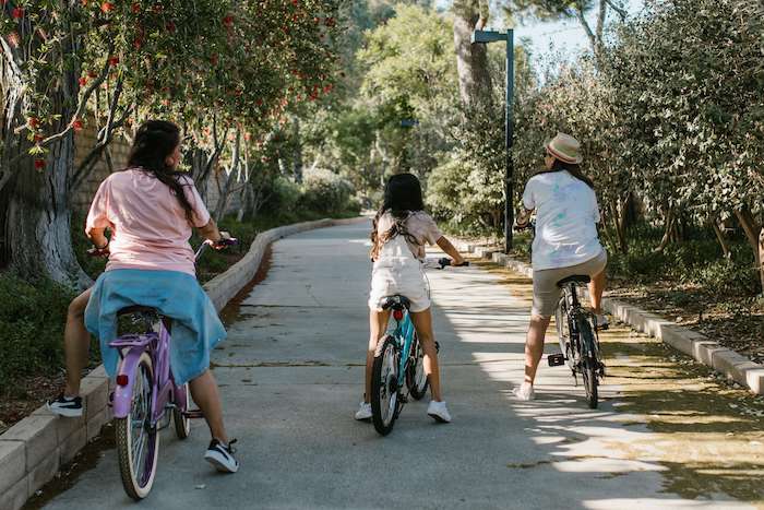 Two women and girl on bikes on a ride through a pavement