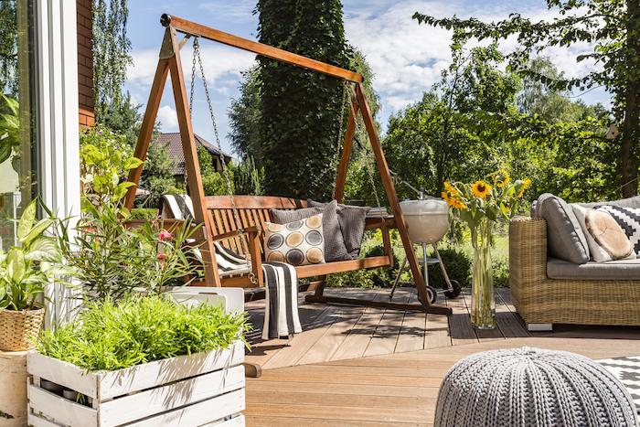 Shot of a wooden garden swing in a house terrace full of plants and flowers