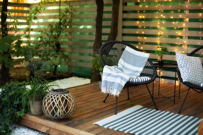 Exterior veranda of house with black Acapulco armchairs plants pots cosy space