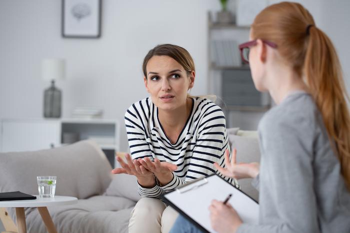 Confused young woman with social problem during psychologist meeting
