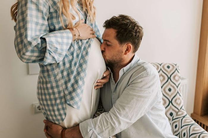 man kissing pregnant woman's belly