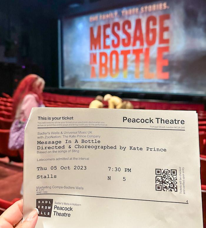 Message Theatre - Holding ticket with seats with the stage as a background