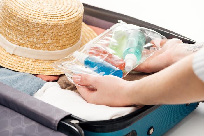 Cropped view of woman packing travel bag with cosmetic bag with bottles - stock image