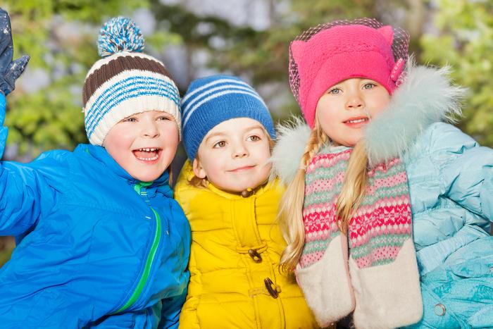 Happy laughing boys and girl in winter clothing close portrait outside