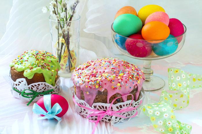 Easter cakes with icing sugar, colorful painted eggs and bouquet of fluffy willow twigs on table. Traditional Easter treats of Russia and Ukraine for Orthodox Easter. Easter symbols