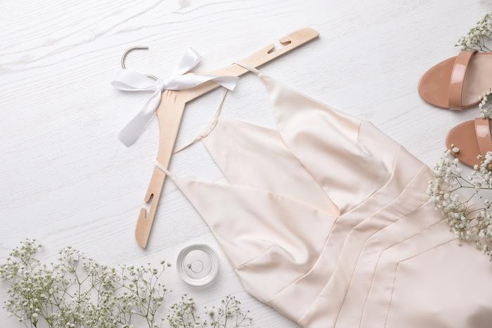 Beautiful dress, engagement ring and flowers on white wooden background, flat lay