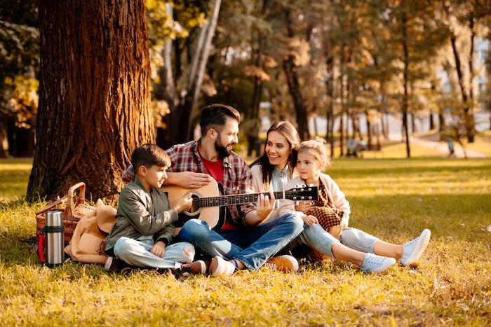 Family on picnic playing guitar