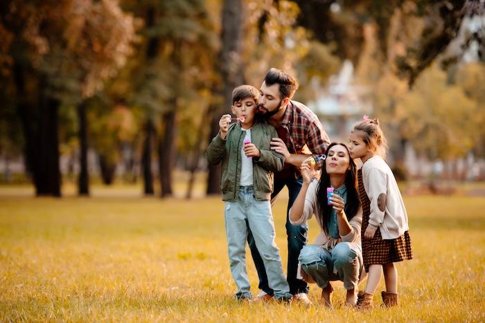 How to Encourage Kids to Spend More Time Outdoors in 4 Simple Steps. Parents with children blowing bubbles