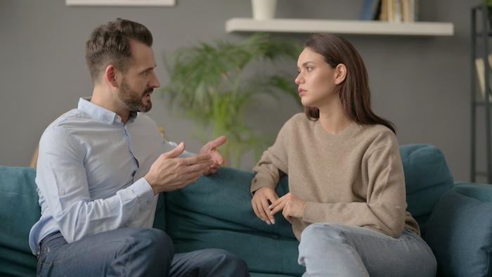 Young Couple having Serious Conversation while Sitting on Sofa