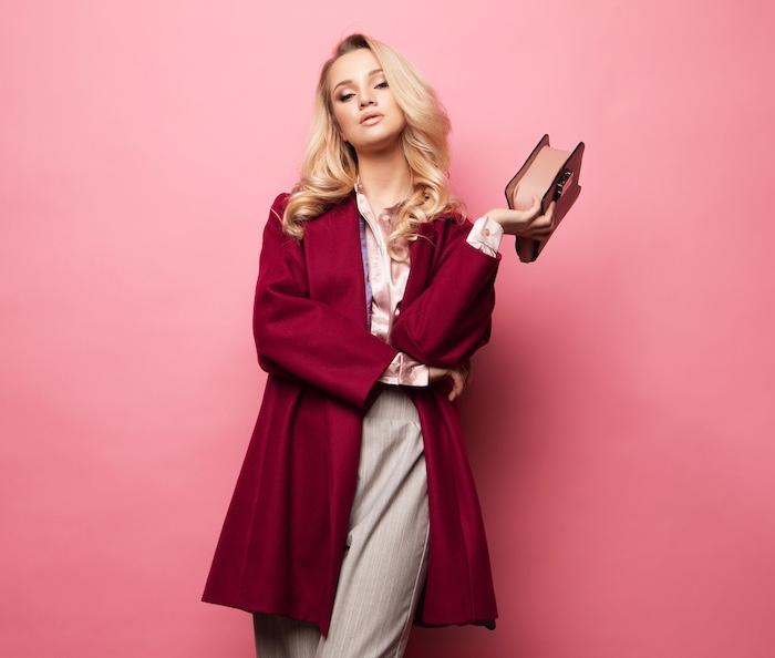Beautiful sweet young blond woman posing in nice clothes, red coat, handbag. Spring fashion concept.