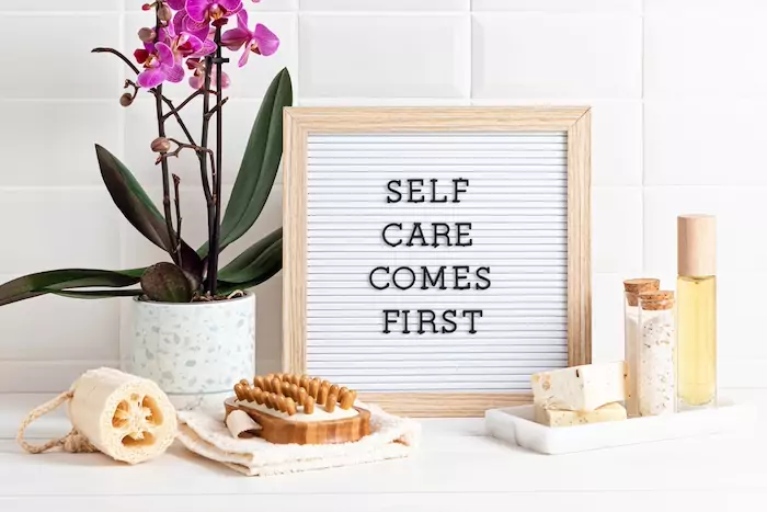 Finding Time for Self-Care When the Family Schedule Feels Overwhelming. Bathroom styling and organization. Letter board with text Self care comes first. Organic lifestyle and skin care products.