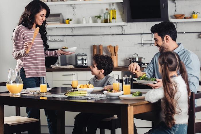 latin woman looking at son while holding plate near daughter and husband during lunch