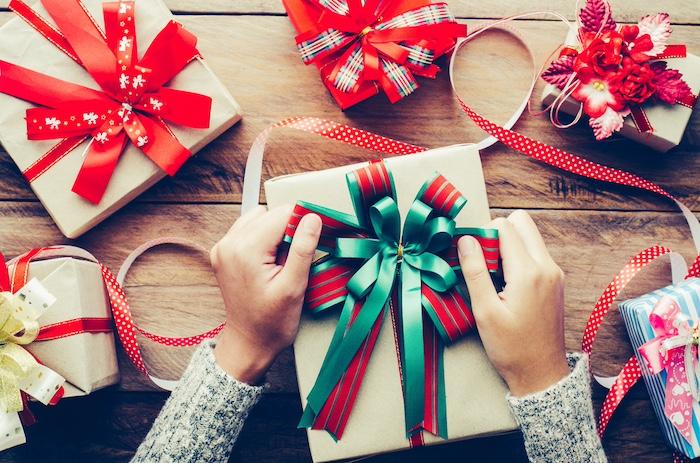 Christmas Gifts for Her 2025: 10 Stylish & Trendy Lifestyle Picks. Hand are wrapping gifts for a special festival on a wooden table