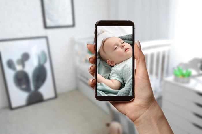 Mother using modern mobile phone as baby monitor at home