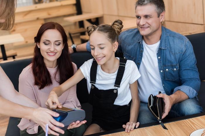 Teen paying at a cafe with parents