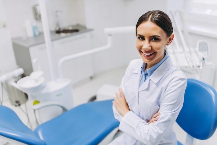overhead view of smiling female dentist ith crossed hands looking at the camera in dental clinic