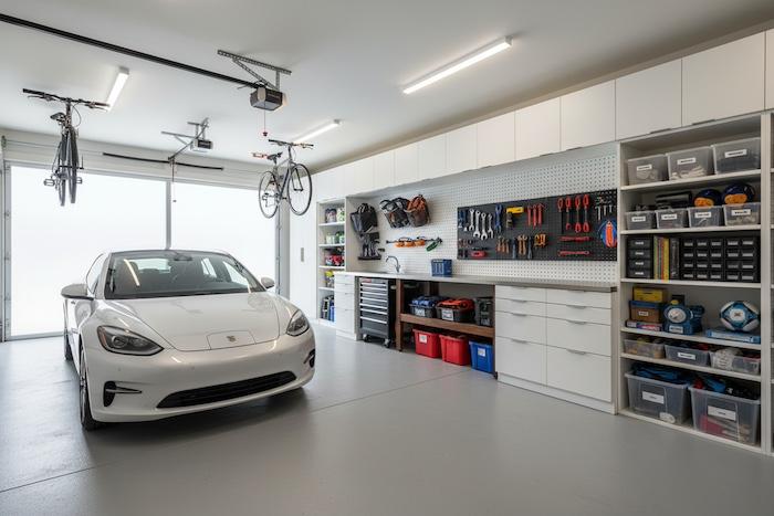 bright and organised garage space with storage systems, tools on wall, tidy floor, modern home garage, natural light, realistic photography style