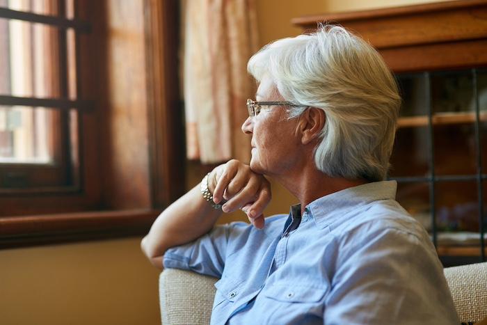Cropped shot of a senior woman looking out the window at home.