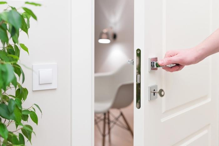 To open the door. Modern white door with chrome metal handle and a man's arm. Elements of interior closeup.