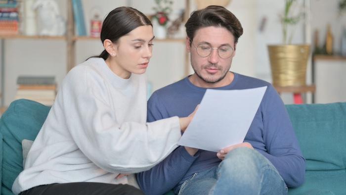Young Couple Reading Documents Together on Sofa