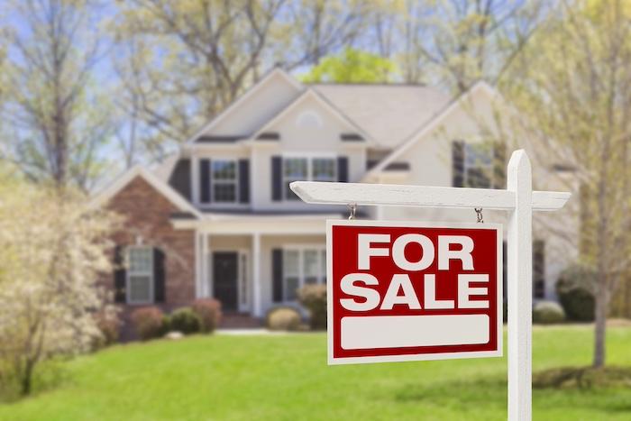 Is It Worth Selling Your House to a House Buying Company?. Home For Sale Real Estate Sign and House