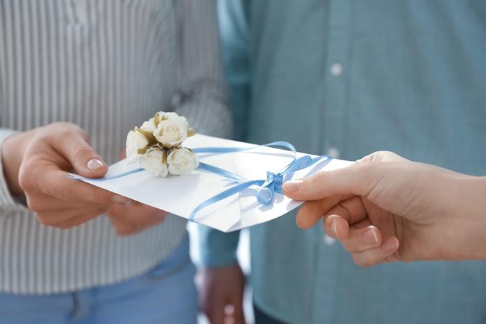 Couple receiving wedding invitation, closeup