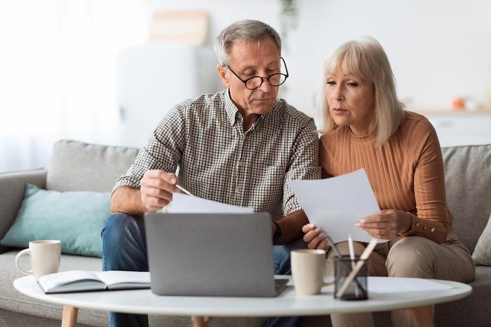 Senior Couple Looking Through Finance documents At Home