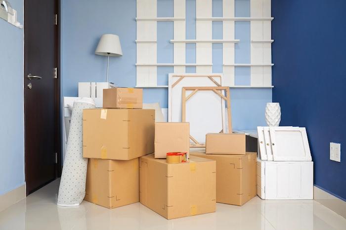 Multiple carton boxes with household stuff and furniture in empty room of new apartment