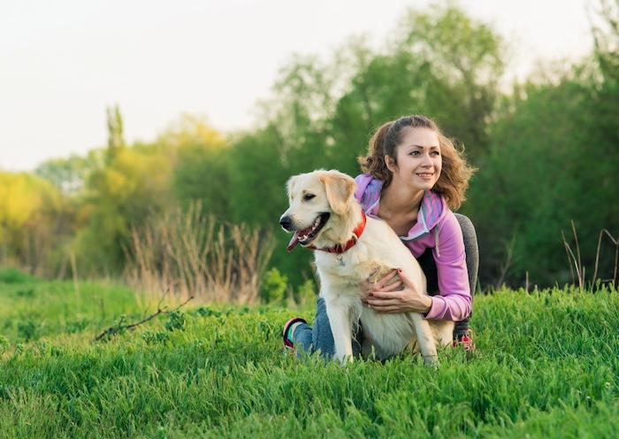 Portrait of young beautiful woman lying and hugging her golden retriever dog. Happiness and friendship. pet and woman.
