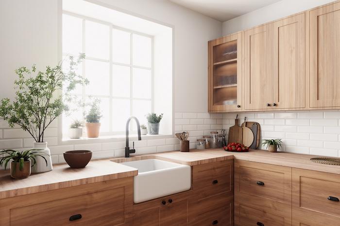 A warm and cozy kitchen that features beautiful wood cabinets, a classic farmhouse sink, and vibrant lush greenery