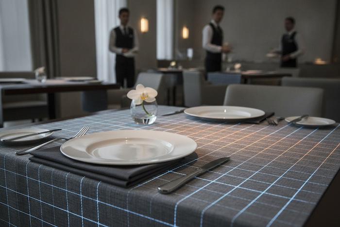 Close-up of smart fabric tablecloth in a modern restaurant, subtle textile technology, clean table setting, professional hospitality environment