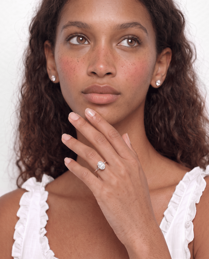Woman wearing a lab-grown diamond engagement ring with a round-cut stone on her finger.