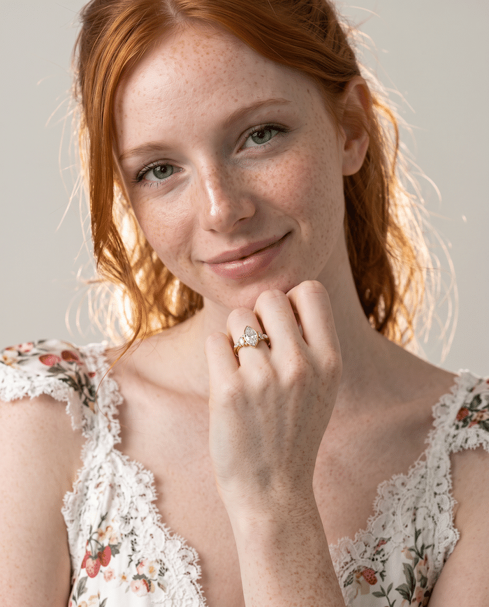 Woman wearing a gold engagement ring with a diamond setting, showing the ring on her hand.